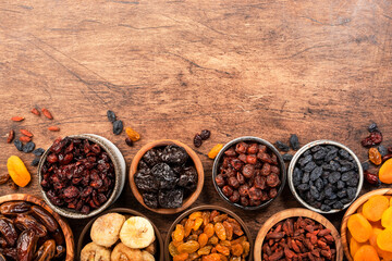 Wall Mural - Natural Dried fruits in bowls. Healthy food snack: sun dried organic mix of apricots, figs, raisins, dates and other on wooden table, top view