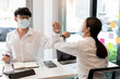 © snowing12 - two business partners wearing protective mask touching elbows together agreed to work on the new project