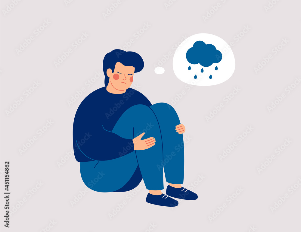 Unhappy man hugs his knees and sits on the floor with rainy cloud above ...