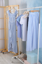 Rack With Stylish Clothes Near Light Blue Wall Indoors