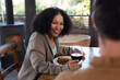 © Wavebreak Media - Happy diverse couple in living room sitting at table eating dinner together and drinking wine