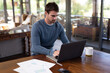 © Wavebreak Media - Caucasian man sitting at table and working remotely using laptop