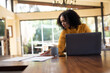 © Wavebreak Media - Mixed race woman sitting at table and working remotely using laptop