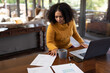 © Wavebreak Media - Mixed race woman sitting at table and working remotely using laptop