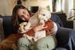 © Wavebreak Media - Portrait of smiling caucasian woman in living room sitting on sofa embracing her pet dogs