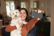 © Wavebreak Media - Smiling caucasian woman in living room embracing her pet dog taking selfie