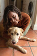 © Wavebreak Media - Smiling caucasian woman in kitchen sitting on floor and embracing her pet dog