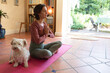 © Wavebreak Media - Caucasian woman in living room with her pet dog, practicing yoga, meditating