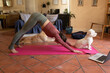 © Wavebreak Media - Caucasian woman in living room with her pet dogs, practicing yoga, using laptop