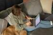 © Wavebreak Media - Caucasian woman in living room, sitting on sofa with her pet dog, using laptop