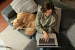 © Wavebreak Media - Caucasian woman in living room, sitting on sofa with her pet dog, using laptop
