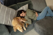 © Wavebreak Media - Smiling caucasian woman in living room, lying on sofa with her pet dog