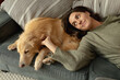 © Wavebreak Media - Smiling caucasian woman in living room, lying on sofa with her pet dog