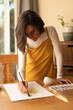 © Wavebreak Media - Caucasian woman in living room, sitting at table painting