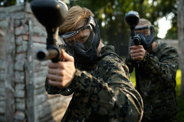 Paintball players aimimg with guns from shelter