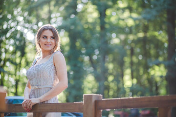 Canvas Print - Shallow focus vertical shot of a beautiful female near a fence in a silver dress