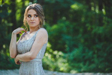 Poster - Shallow focus shot of a Caucasian woman posing in a silver dress in a sunlight