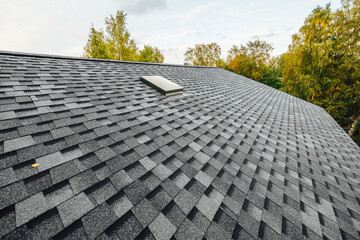 roof of new house with shingles roof-tiles and ventilation window