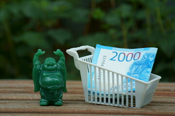 A figure of a happy Buddha and a basket with money in close-up. A financial symbol. Well-being.