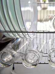 Wall Mural - Closeup view of glasses and plates washed and put on the racks in the kitchen