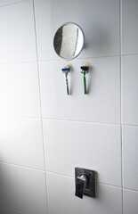 Wall Mural - Closeup view of mirror, razors on wall and the head of the tap of the shower on the wall