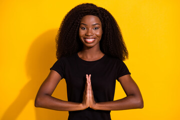 Sticker - Photo of cheerful happy young afro american woman hold hands clap wish isolated on yellow color background