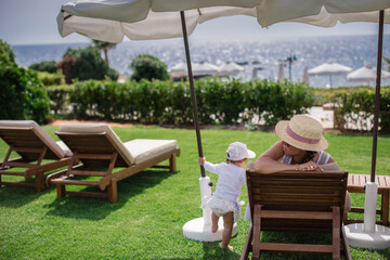 Wall Mural - Lovely little girl with mother at summer resort.