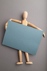 Wall Mural - Wooden mannequin holding blue blank poster on gray pastel background. copy space.