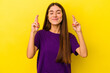 © Asier - Young caucasian woman isolated on yellow background crossing fingers for having luck