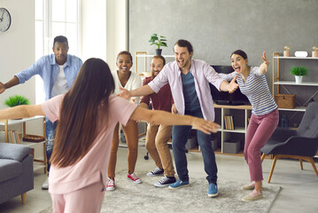 Long time no see. Group of young people are very excited to finally meet their friend who's been away and is back home again. Happy woman spreading arms wide open to hug her friends she missed so much