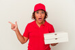 © Asier - Middle age delivery woman taking pizzas isolated on white background pointing to the side