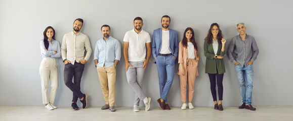 People in modern business. Portrait of a team consisting of men and women of different ages standing in a row near the wall. Happy smiling people who are determined to succeed and achieve results.