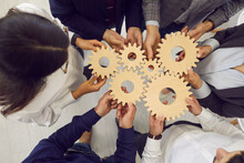 Overhead View On Diverse Business Team People Hands Holding Gear Wheels Finding Working Solutions. Power Partnership, Engineering Teamwork, Manage Team Work And Company Activities Concept