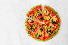 Healthy, Gluten Free Broccoli Crust Pizza With Tomatoes, Zucchini And Mushrooms. Top View With Cut Slices On A White Marble Background.