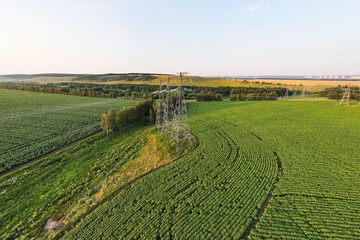 Transmission line in rural field. High-voltage tower for electrical grid in aerial view