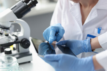 scientists in sterile gloves hold tablet in laboratory closeup