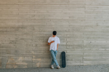 Poster - teen boy with mobile phone and skateboard on the wall with copy space