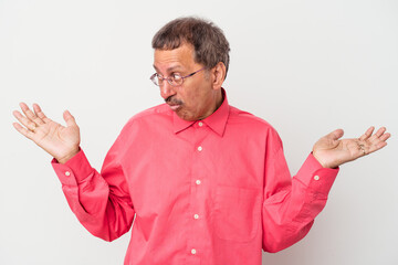 Wall Mural - Middle aged indian man isolated on white background confused and doubtful shrugging shoulders to hold a copy space.