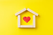 © Andrii - house shape made by wooden blocks with red heart inside over yellow background. outer space. real estate concept