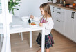 © Galina Zhigalova - Pretty little girl with long hair puts on vegetable salad in kitchen with bright interior at home