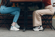 The Bottom View Of Two Woman Legs Sitting At Table In Street Cafe