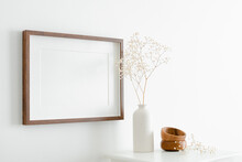 Horizontal Wooden Frame Mockup With Copy Space For Artwork, Photo Or Print Presentation. White Wall With Furniture And Dry Gypsophila Plant.