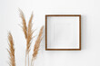 © nikavera - Blank square frame with passepartout mockup on white wall with dry plant decorations. Minimalistics style interior with artwork mockup.