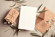© nikavera - Greeting card mockup with gift box, envelope and eucalyptus and gypsophila twigs on beige background.