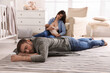 © New Africa - Tired young parents with their baby sleeping on floor in children's room