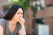 © PheelingsMedia - Asian woman coughing in the street