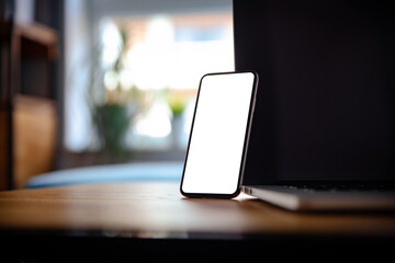 Wall Mural - a smartphone with a blank screen with tags stands leaning against a laptop