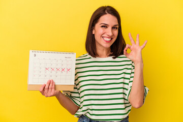 Young australian woman holding a calendar isolated on yellow background cheerful and confident showing ok gesture.