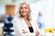 © gzorgz - Portrait of beautiful grey haired senior businesswoman standing at the office while looking at camera and smiling.