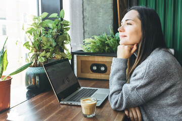 Handsome freelancer in glasses with laptop during coffee break dreaming about future near window.